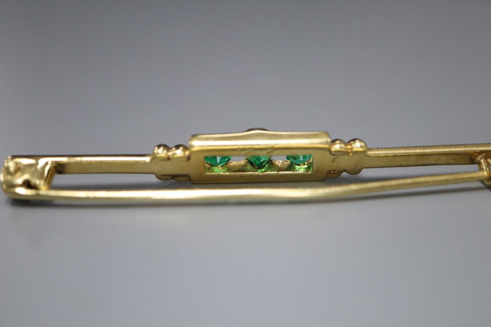 A yellow metal and three stone emerald set tie pin, 52mm, gross 5.4 grams.